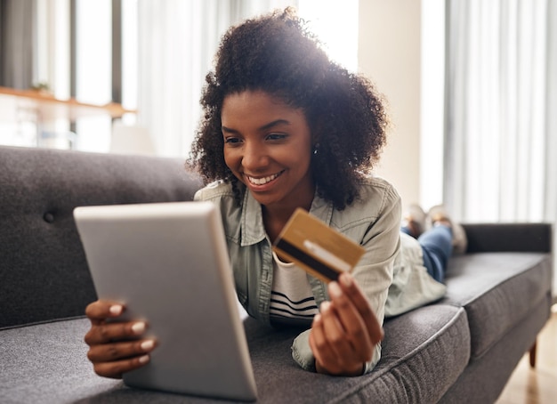 Relaja la tableta y la mujer africana con tarjeta de crédito en el sofá para transacciones de comercio electrónico o compras en línea en la sala de estar Aplicación de pago y persona para compras suscripción o banca por Internet en el hogar