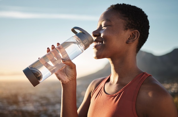 Relajación en el agua y entrenamiento de mujeres negras en la naturaleza feliz caminata y progreso físico en Taiwán Hidratación sedienta y corredora africana con una bebida después del ejercicio deportivo y el entrenamiento matutino