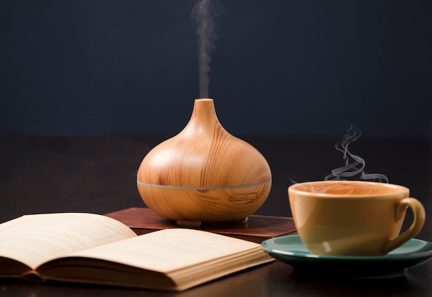 Relajación en casa con difusor de aceite de aromaterapia taza de té amarillo libro abierto Aroma esencia de salud