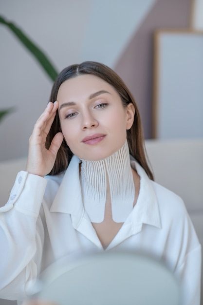 Relajación. Linda mujer joven haciendo masaje facial y mirando relajado