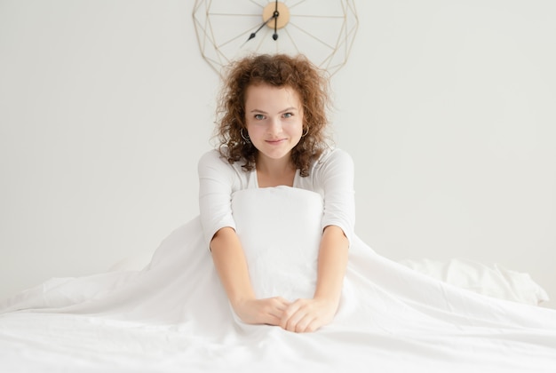 Relajación sonriente joven de la mujer hermosa después de despertarse por la mañana en dormitorio