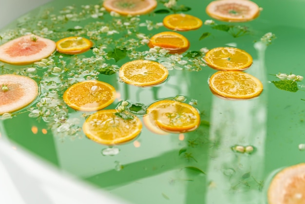 Relajación de spa orgánico en un baño de aromas con flores y rodajas de naranja