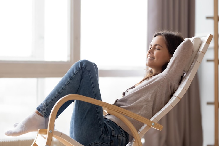 Foto relajada mujer joven tranquila descansando sentada en una cómoda silla de balanceo de madera respirando aire fresco soñando feliz niña perezosa relajándose disfrutando sin estrés un fin de semana tranquilo y tranquilo en casa