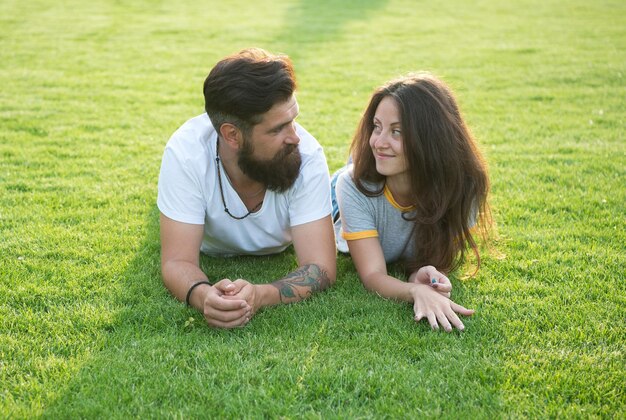 Relajado y enamorado. Par relajarse en la hierba disfrutando unos de otros. Hombre barbudo hipster y mujer bonita enamorada. Vacaciones de verano. Enamorarse. Felicidad veraniega. Felices juntos. Pareja enamorada.