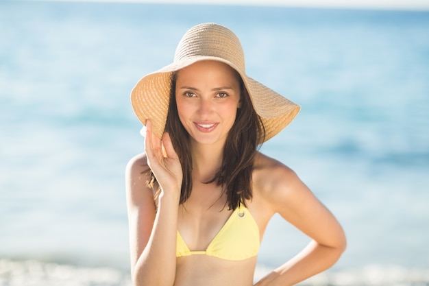 Relajante morena con un sombrero de paja sonriendo a la cámara