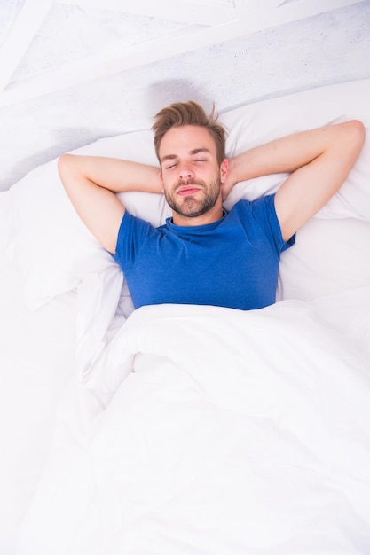 Relajarse antes de dormirse. Duerma lo suficiente cada noche. Cara de hombre barbudo relajante. Mantener un ritmo circadiano constante es esencial para la salud general. Hombre guapo relajante en la cama.