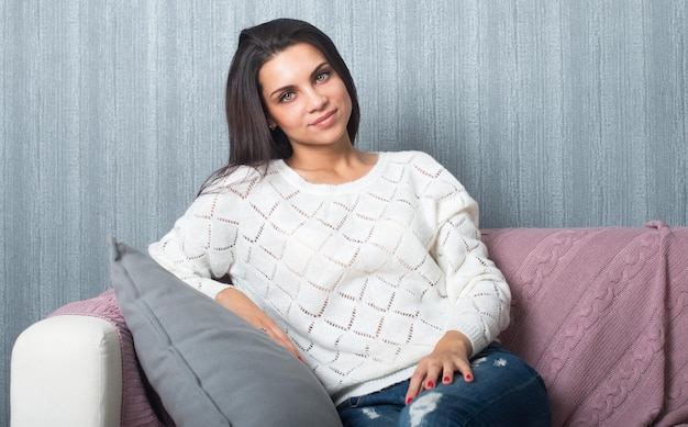 Relajarse en la comodidad del hogar linda mujer joven sonriendo relajándose en el sofá blanco en casa