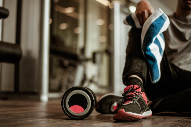 Relajarse después de entrenarhermoso joven mirando hacia otro lado mientras está sentado en el gimnasio