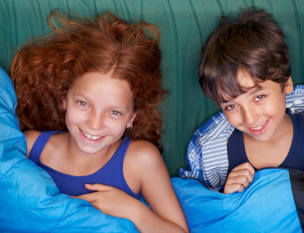 Relajarse en su tienda Retrato de un hermano y una hermana jóvenes acostados y sonriendo