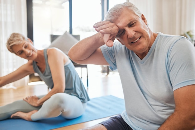 Relajarse yoga y pareja senior con hombre cansado descansando en la alfombra con fatiga del ejercicio físico Feliz casada y mujer jubilada riéndose del marido agotado del entrenamiento de pilates en casa