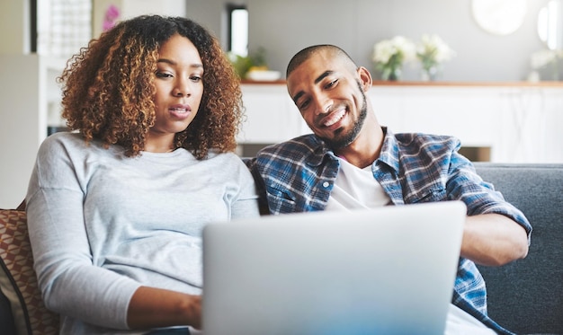 Relájese con una computadora portátil y una pareja feliz en el sofá en la sala de estar para conversar en redes sociales o navegar por Internet Lens flare hombre y mujer casados para elegir suscripción o compras en línea en el hogar