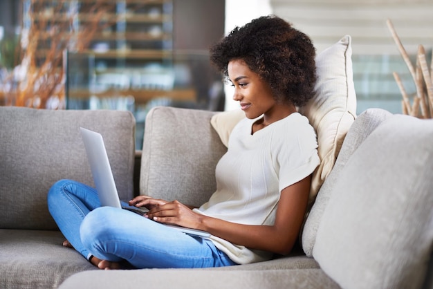 Relájese escribiendo y mujer en un sofá portátil y busque un sitio web en casa felicidad y red Modelo de persona femenina en un salón y dama con tecnología escalofriante y lectura en línea en vacaciones de fin de semana