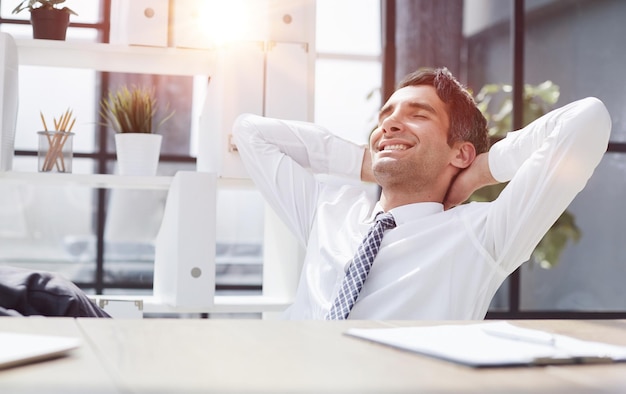 Relájese, estírese y feliz hombre de negocios en la mesa en la planificación del trabajo y la oficina o el trabajo