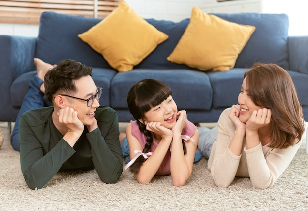 Relájese familia asiática tendida con feliz y sonrisa en la alfombra en la sala de estar en casa vista superior