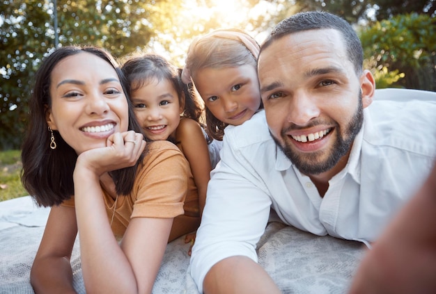 Relájese feliz y tome selfies con la familia en un picnic para apoyo de verano o unión en el parque Sonría libertad y cariño con el retrato de padres e hijos en el césped en el campo para la alegría y la naturaleza