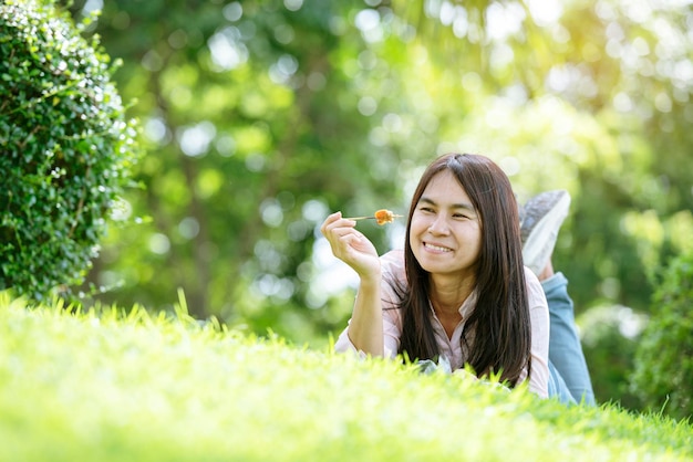 Foto relájese hermosa mujer asiática cara sonriente acostada en el campo de hierba verde en el parque del jardín al aire libre disfrute de la naturaleza mañana libertad mujer de estilo de vida respirando aire fresco en el parque verde en el césped de primavera al aire libre