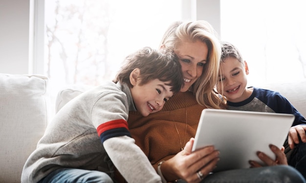 Relájese con la tableta y la mamá con los niños en el sofá, uniendo tiempo de calidad y transmitiendo películas el fin de semana. Ame el hogar familiar y la mamá y los niños con tecnología digital para el aprendizaje de juegos en línea y la aplicación de Internet.