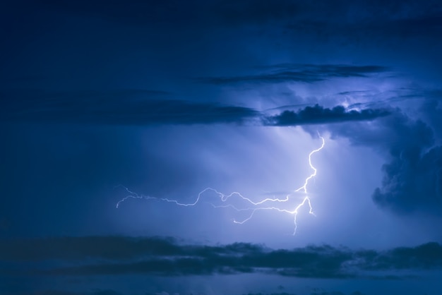 Relâmpago de tempestade de trovão no fundo escuro do céu nublado à noite.