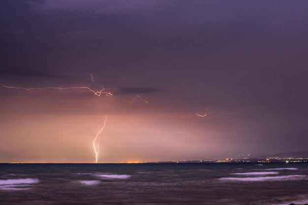El relámpago sobre el mar contra el cielo por la noche