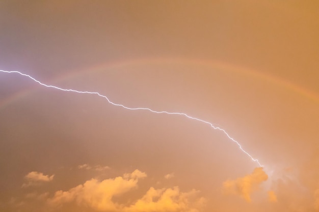 Relâmpagos à noite em um céu tempestuoso e um arco-íris durante tempestades