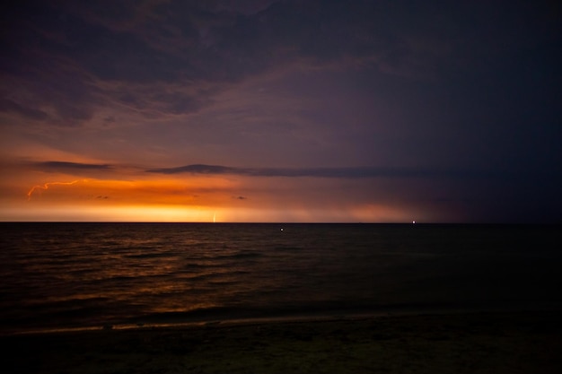 Relâmpagos iluminam o céu à noite no mar