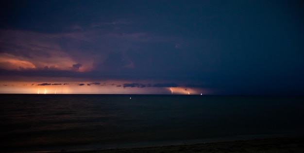 Los relámpagos iluminan el cielo por la noche en el mar.