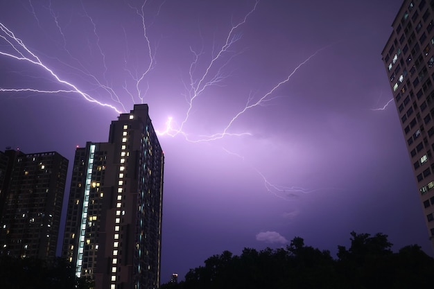 Relâmpagos reais espetaculares no céu noturno urbano roxo escuro