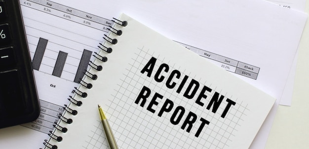 Relatório de acidente de texto na página de um bloco de notas sobre gráficos financeiros na mesa do escritório
