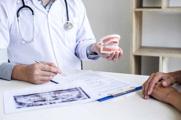 relatório de escrita de médico ou dentista trabalhando com modelo de filme de raio-x de dente e equipamentos utilizados no tratamento de odontologia e odontologia