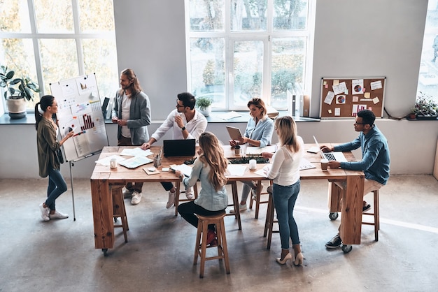 Relatório de vendas. Vista superior de dois jovens colegas modernos conduzindo uma apresentação de negócios enquanto estão na sala da diretoria