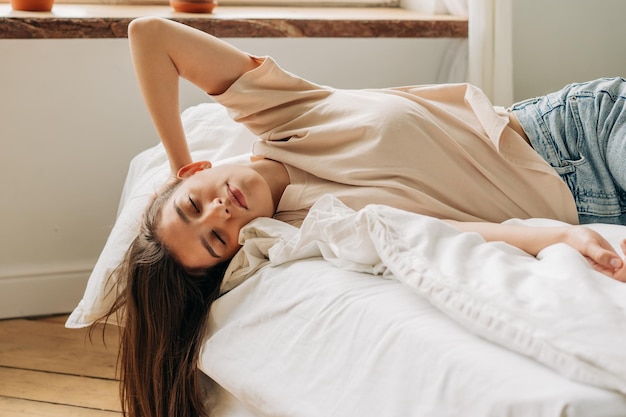 Relaxada mulher bonita deita-se na cama o conceito de solidão e melancolia