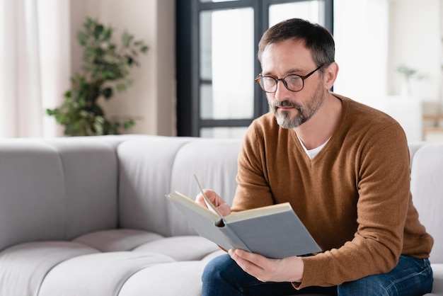 Relaxado, pensativo, homem maduro de meia-idade, pai, marido, autor, tutor freelancer, estudante adulto, professor, lendo livros em casa, preparando-se para exames na universidade, desfrutando de romances no tempo livre.