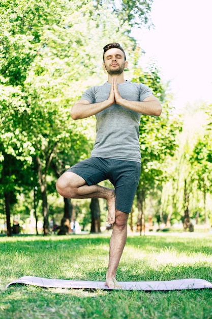 Relaxamento de ioga masculina. Jovem bonito desportivo e magro está fazendo exercícios de ioga no parque da cidade ao ar livre. Estilo de vida saudável e corpo e alma fortes