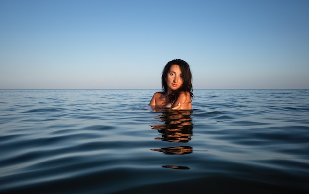 Relaxamento e estilo de vida saudável. Jovem mulher bonita e emocional nada no mar em um dia ensolarado. Retrato na água do mar