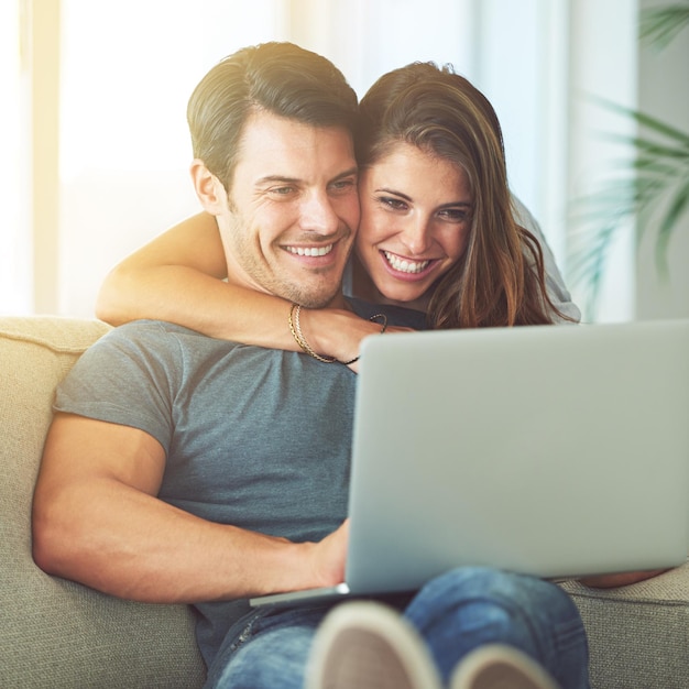 Relaxando junto com algum entretenimento online Foto de um jovem casal afetuoso usando um laptop em casa