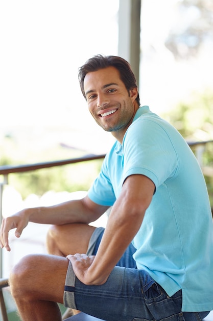 Relaxando no fim de semana Retrato de um homem bonito sentado em uma varanda ao ar livre