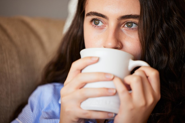 Relaxe calma e mulher tomando café na sala de estar em um sofá em sua casa moderna na Austrália Pensamento de fim de semana e senhora desfrutando de uma xícara de cafeína quente ou bebida de chá em seu lounge