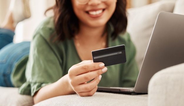 Relaxe compras on-line e cartão de crédito mulher no sofá na sala de estar para internet banking em casa com laptop feliz pagamento de comércio eletrônico sorriso e cashback garota no sofá com computador em venda no site