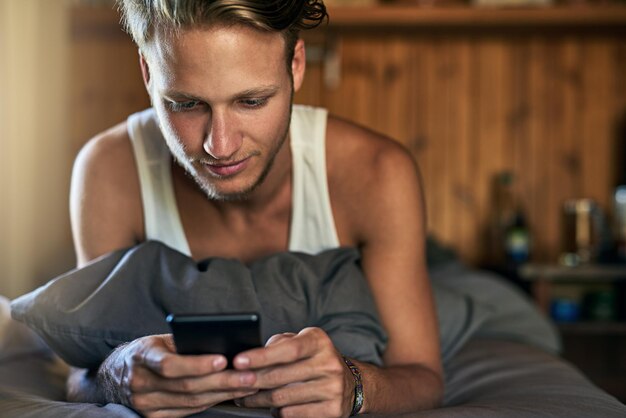 Relaxe em casa e homem na cama com telefone para bate-papo on-line comunicação e networking Apartamento de manhã e pessoa digitando no smartphone para site de mídia social e notícias da internet no quarto