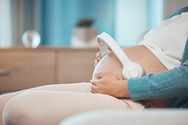 Relaxe música grávida e estômago de uma mulher no sofá para paz calma e som para bebê durante a gravidez Transmissão de amor de rádio e mãe com terapia de áudio com fones de ouvido para criança na barriga