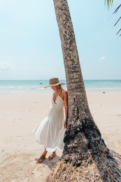 Foto relaxe na praia mulher de pé com uma árvore de coco na praia da ilha