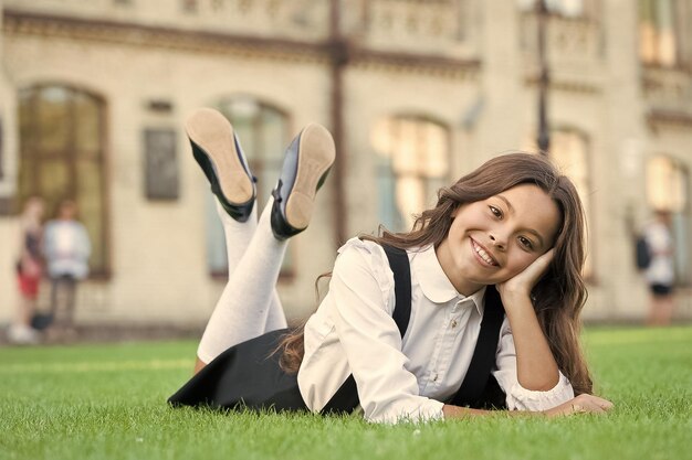 Relaxe no pátio da escola Tempo agradável Intervalo escolar para descansar Aluno sorridente feliz Garota fofa colocando grama verde Garoto feliz relaxando ao ar livre Uniforme escolar de garota aproveite relaxe Estudante alegre