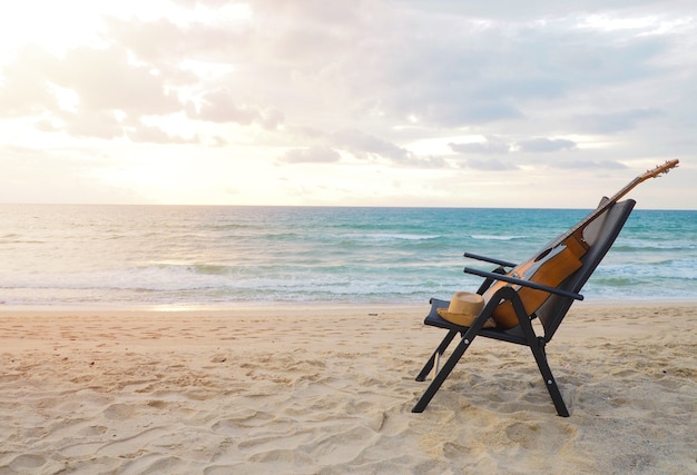 relaxe o tempo, guitarra acústica perto da cadeira de plataforma na praia no por do sol.