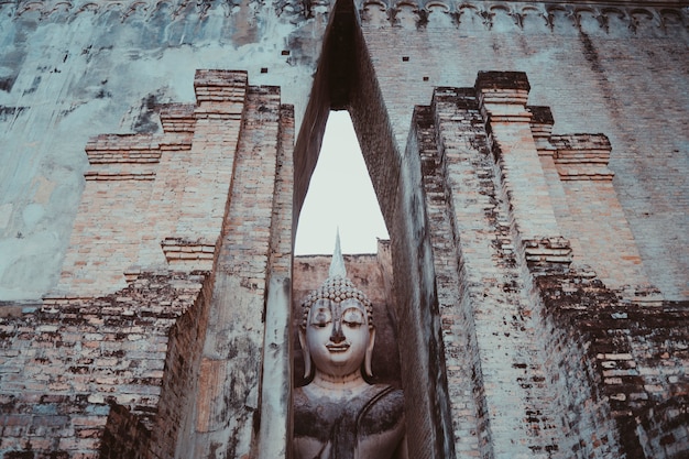 Religião budista, arte antiga e cultura asiática. escultura que senta a imagem de buddha de wat tra phang thong lang no parque nacional de sukhothai em tailândia.