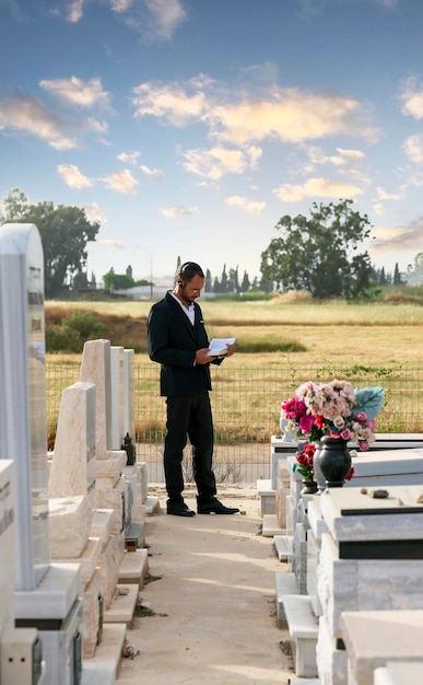 Religiöser Mann Bärtiger Jude in schwarzer Kippa, der eine hebräische Bibel liest, betet Gebet auf einem jüdischen Friedhof in Israel Selektiver Fokus Alter jüdischer Friedhof im Wald Chassidischer Jude, der Thora liest