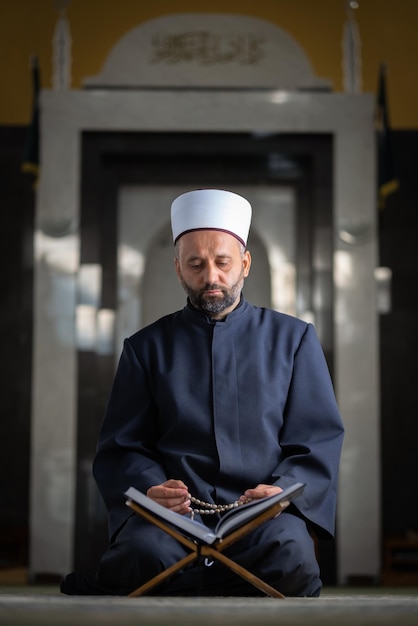 Religiöser muslimischer Mann, der einen Koran liest, während er in der Moschee betet.