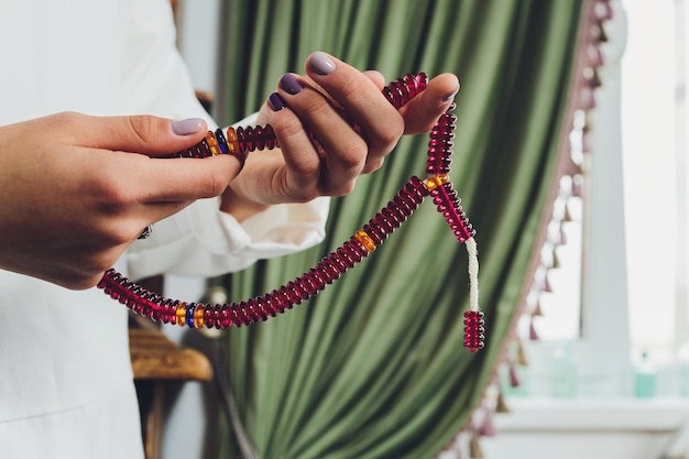 Religiosa mujer budista asiática rezando con la mano sosteniendo cuentas de rosario Discípula budista femenina meditando cantando mantra con rosario rezando en la mano a la estatua del señor Buda en el salón del templo