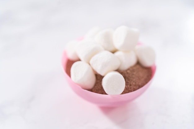 Relleno de conchas de chocolate rosa con mezcla de chocolate caliente y mini malvaviscos para preparar bombas de chocolate caliente