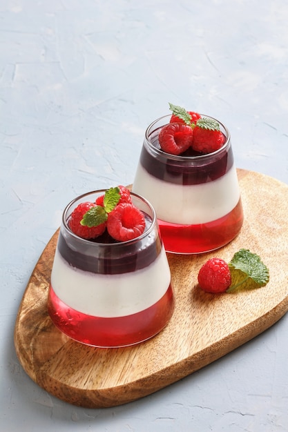 Relleno de gelatina de bayas con frambuesas en un vaso de vidrio sobre un soporte de madera