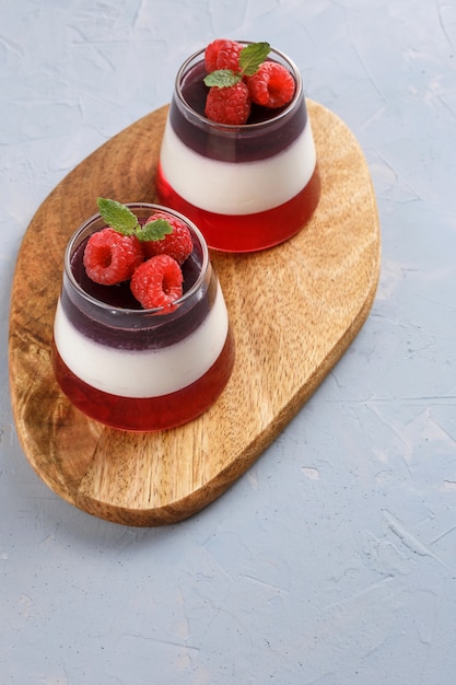 Relleno de gelatina de bayas con frambuesas en un vaso de vidrio sobre un soporte de madera